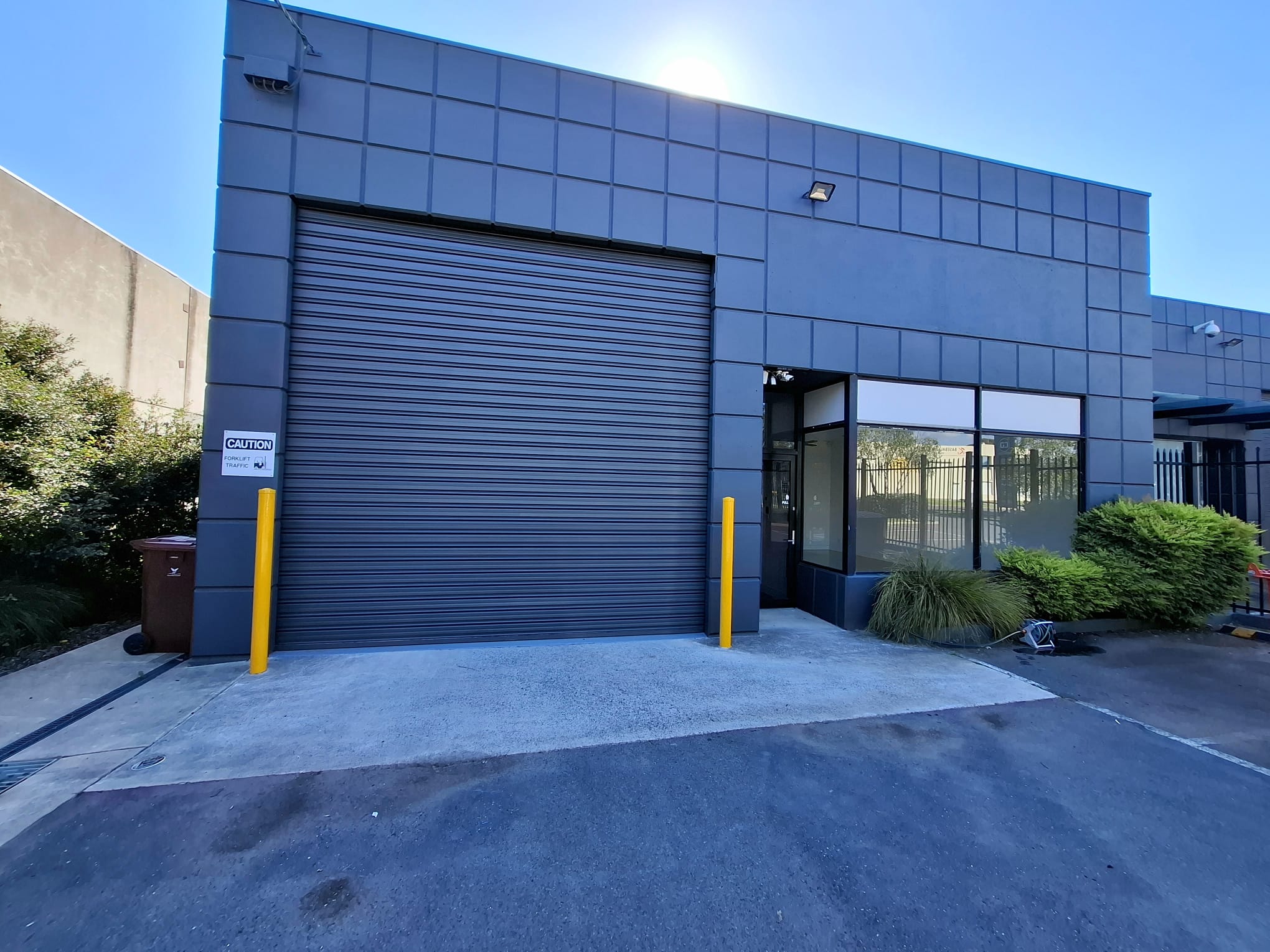 Blue-grey panelled commercial facade with a matching roller door and glazed entry.