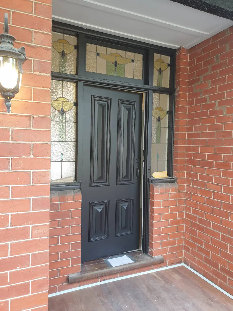 Dark painted front door with decorative glazing and white trim