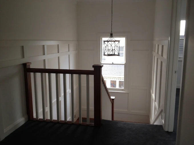 Painted stairwell walls, decorative wall panelling and white balustrade detail