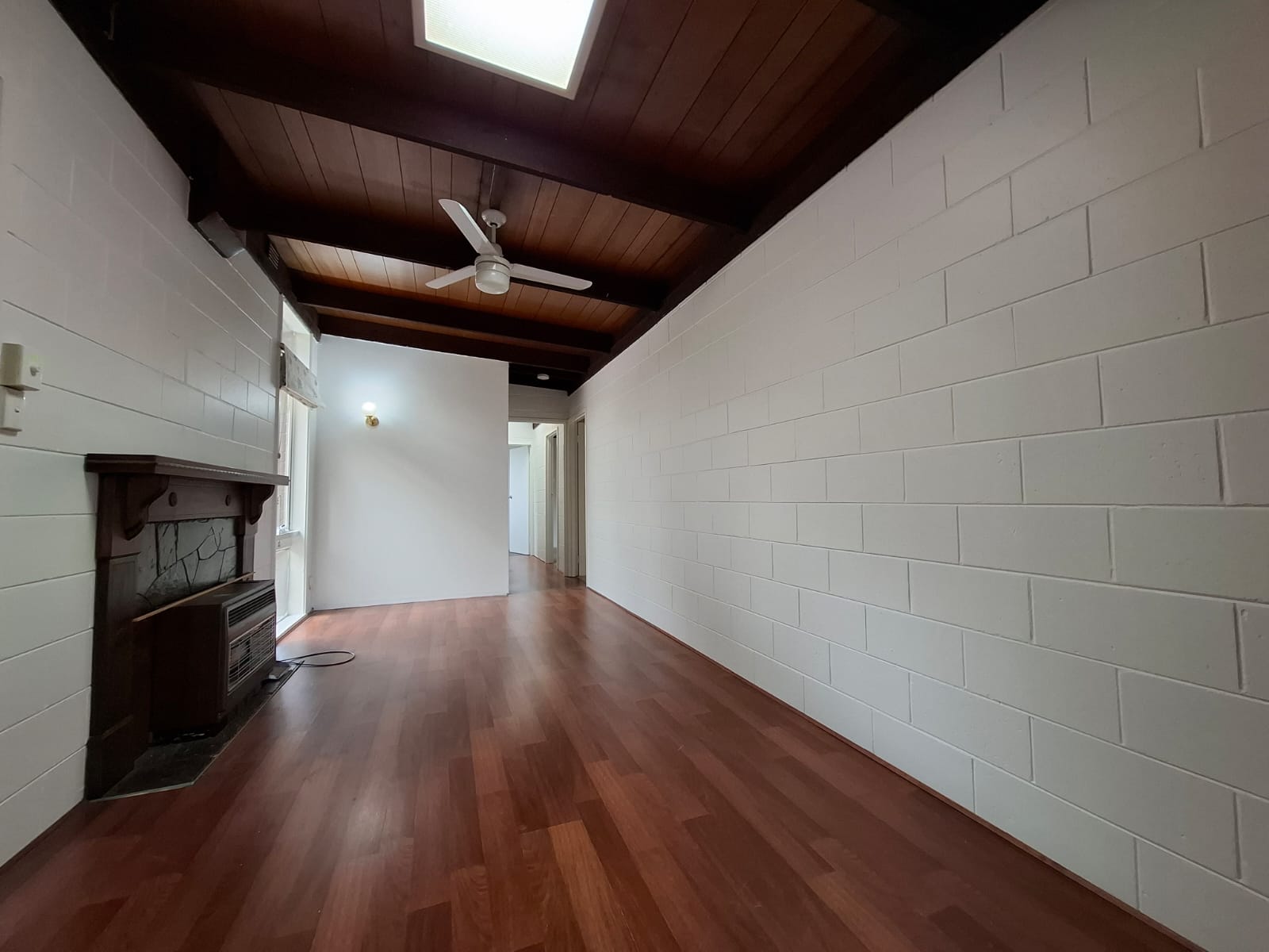 White painted masonry walls in a living room beneath a dark timber ceiling