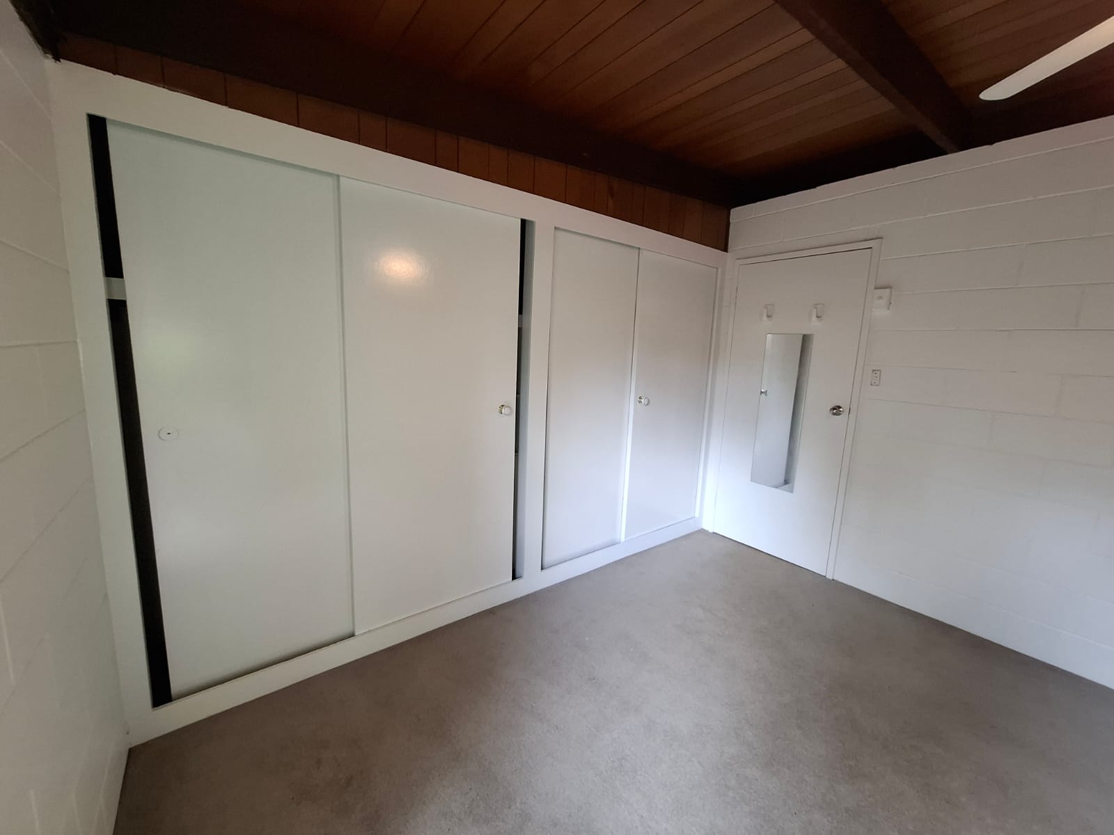 White painted sliding wardrobe doors, bedroom door and masonry walls