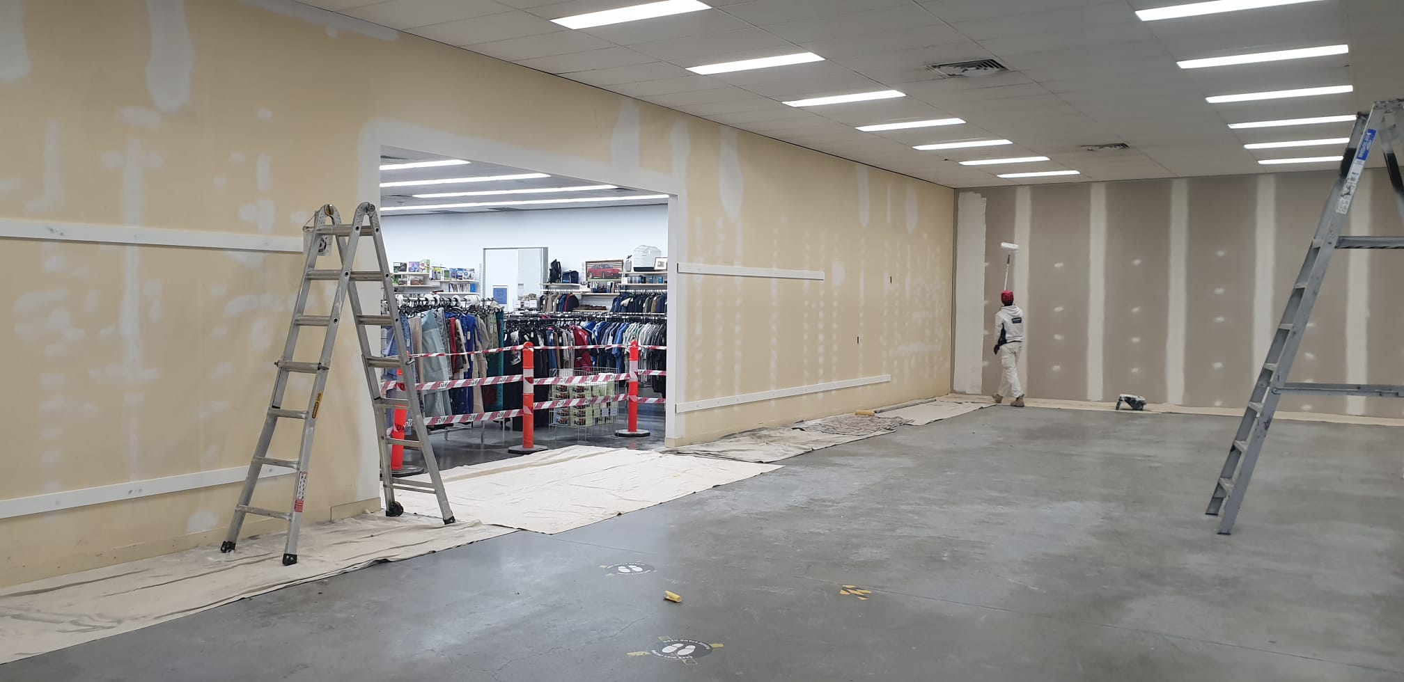 Warehouse interior prepared for painting with protected floors and ladders